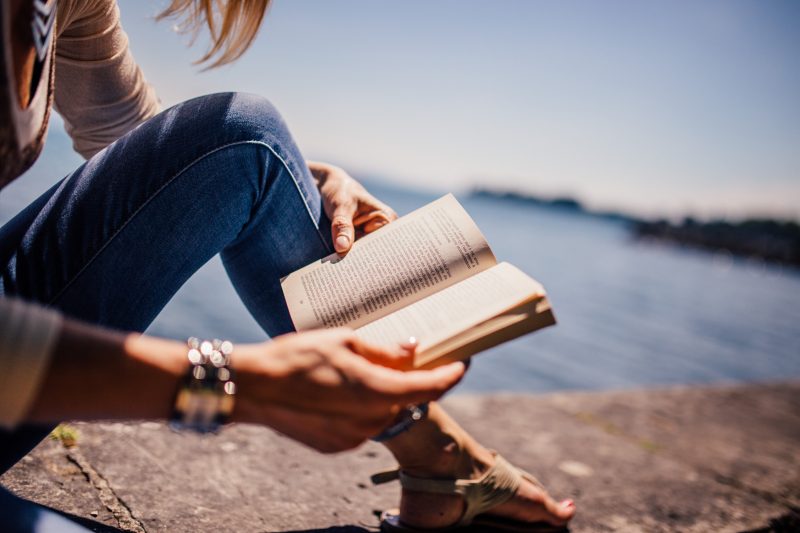 Woman reading book by the water